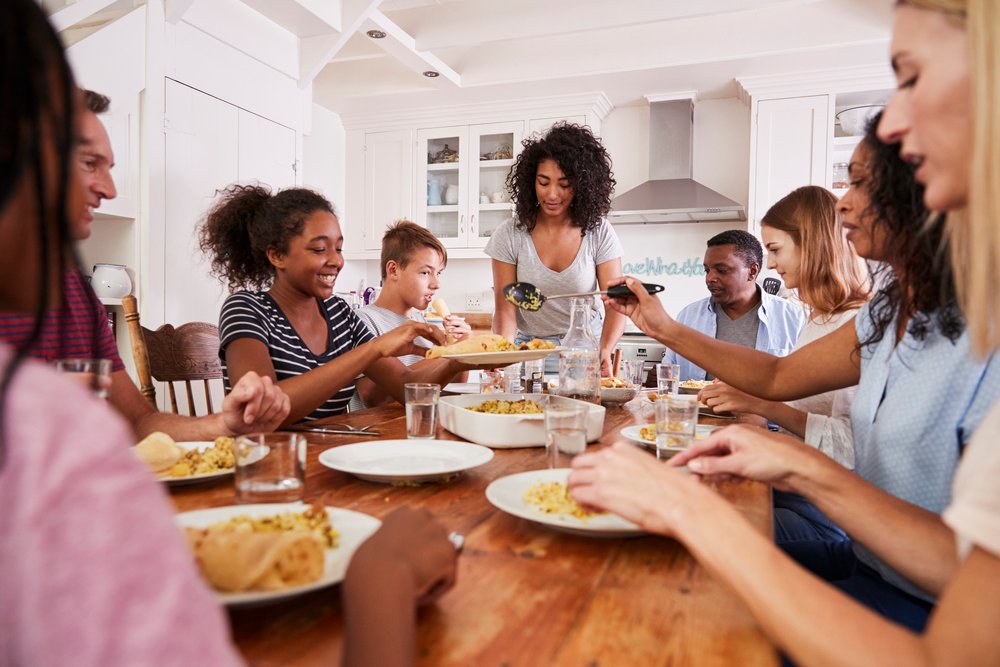 Two Families Enjoying Eating Meal At Home Together