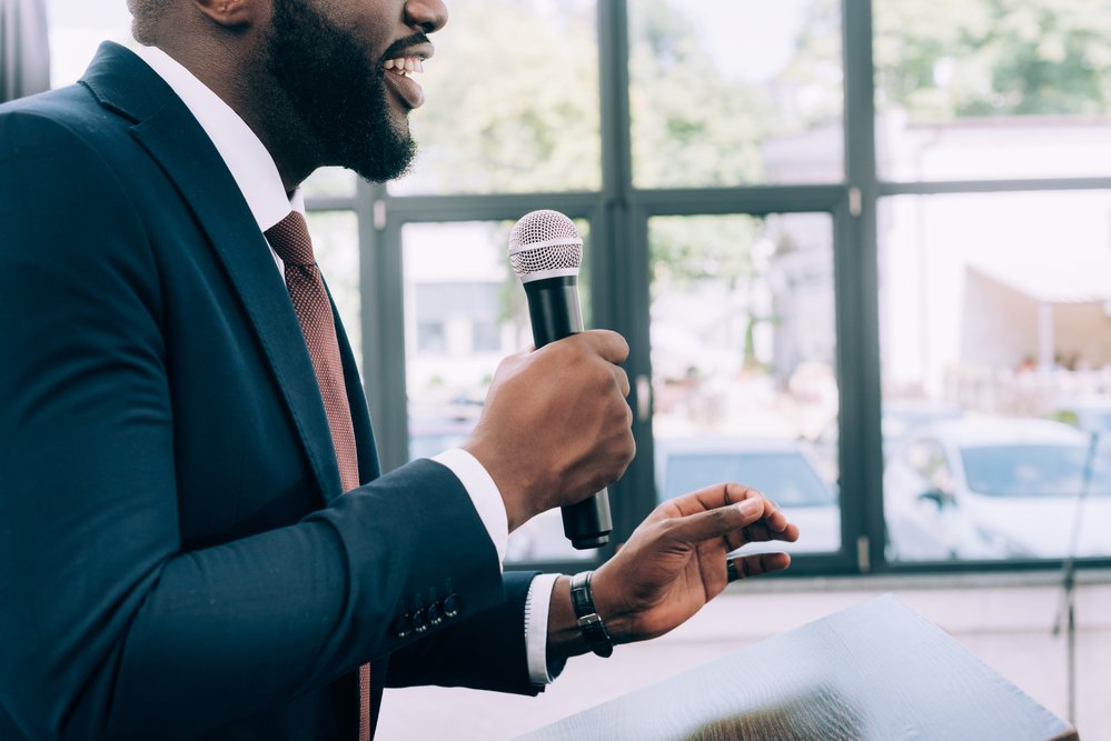 man wearing suit holding mic giving speech