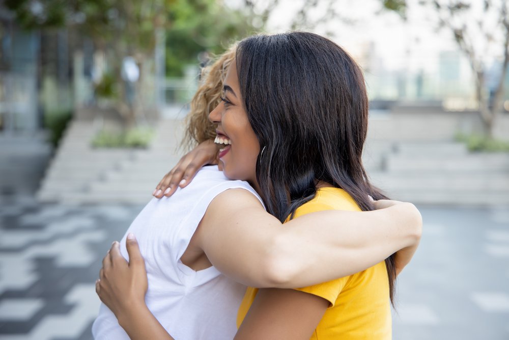 african black woman hugging caucasian white woman friend; concept of skin color tolerance, world peace, ethnicity understanding, international women friends of different skin color and ethnicity