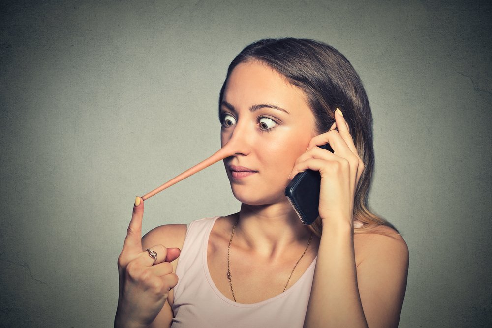 Shocked woman with long nose talking on mobile phone isolated on grey wall background. Liar concept. Human face expressions, emotions, feelings.