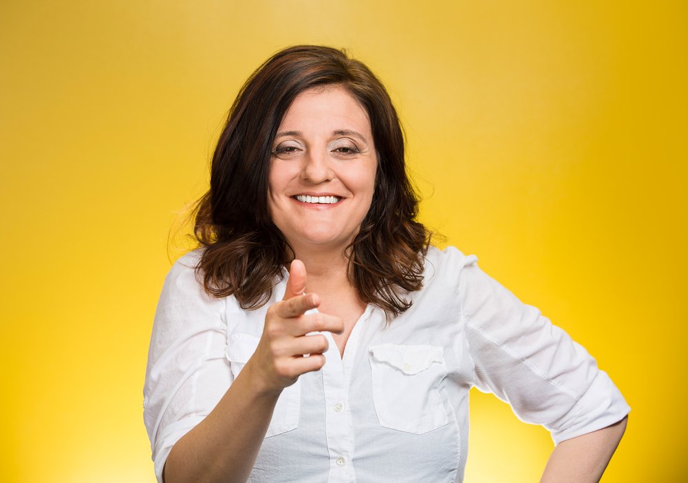 Closeup portrait mature woman laughing smiling pointing finger at someone, something, isolated on yellow background. Positive human emotion facial expression feelings, attitude, reaction