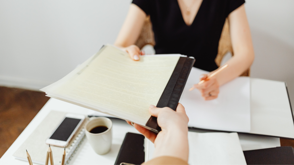 a person handing documents to a woman