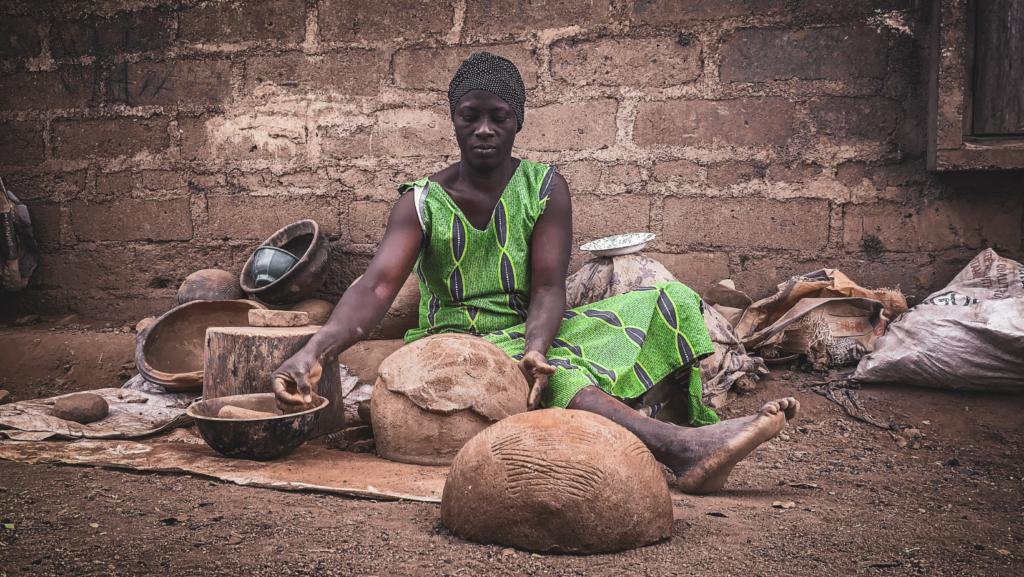 focused black female artisan working with clay on street in poor village