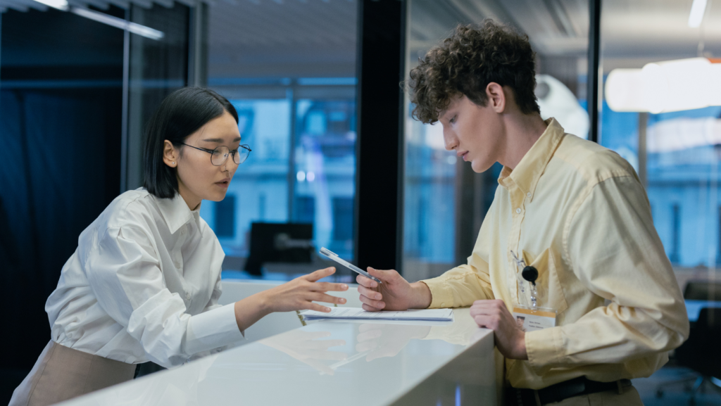 receptionist helping man fill out papers