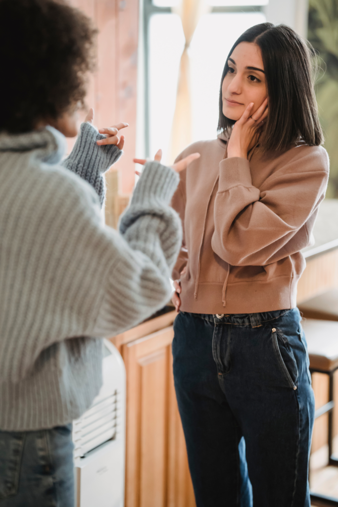 two women standing facing each other, one is arguing while other is looking at her calmly