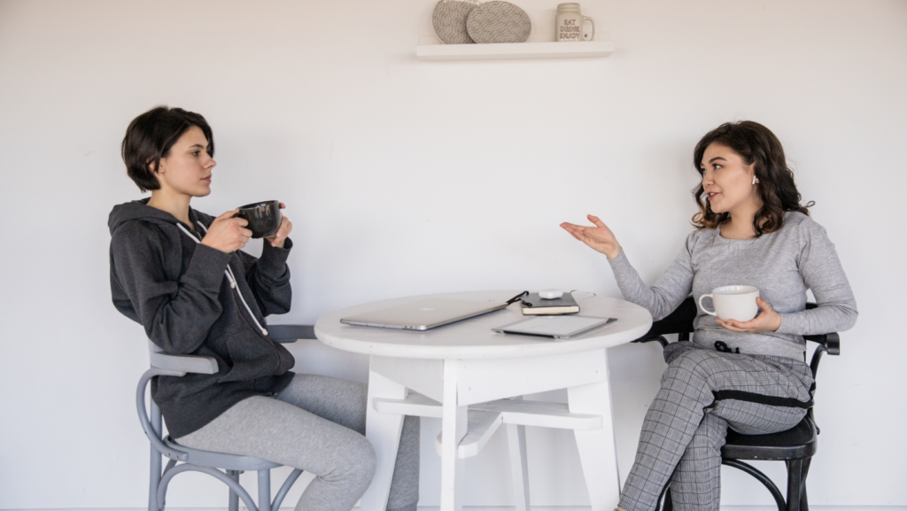 two woman talking to each other having coffee