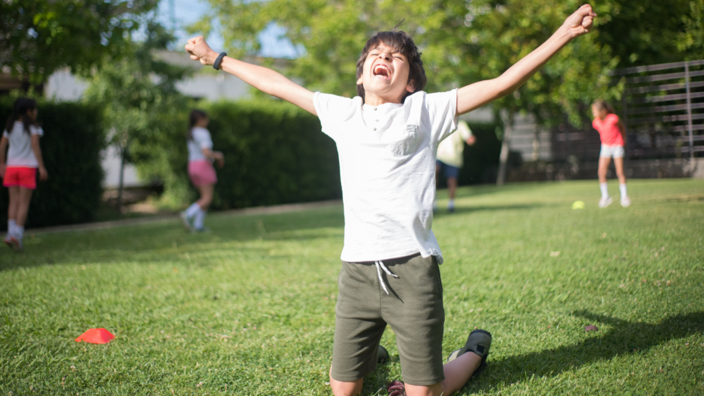 victorious boy kneeling on the grass