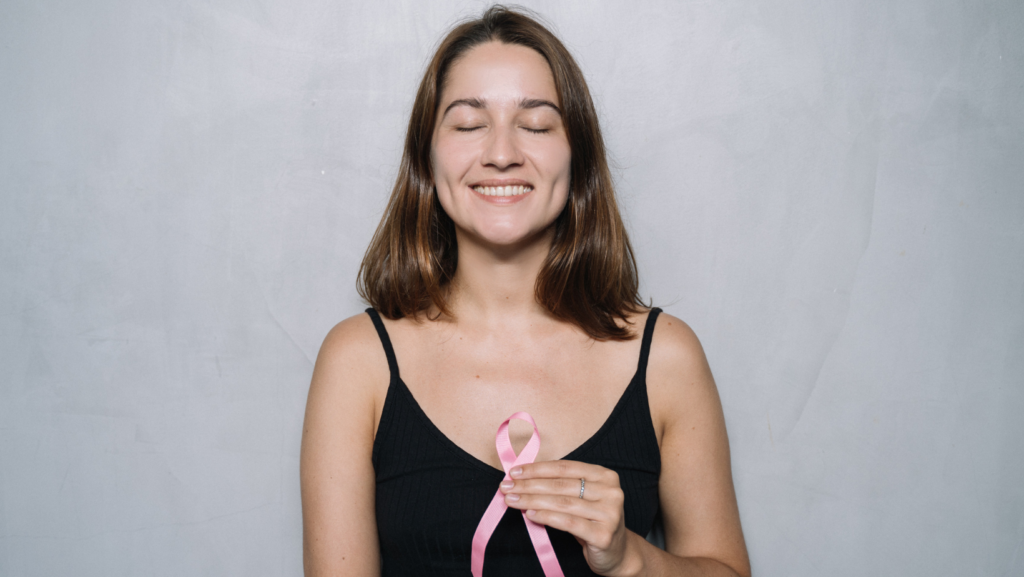 woman black top holding ribbon closed eyes and smiling