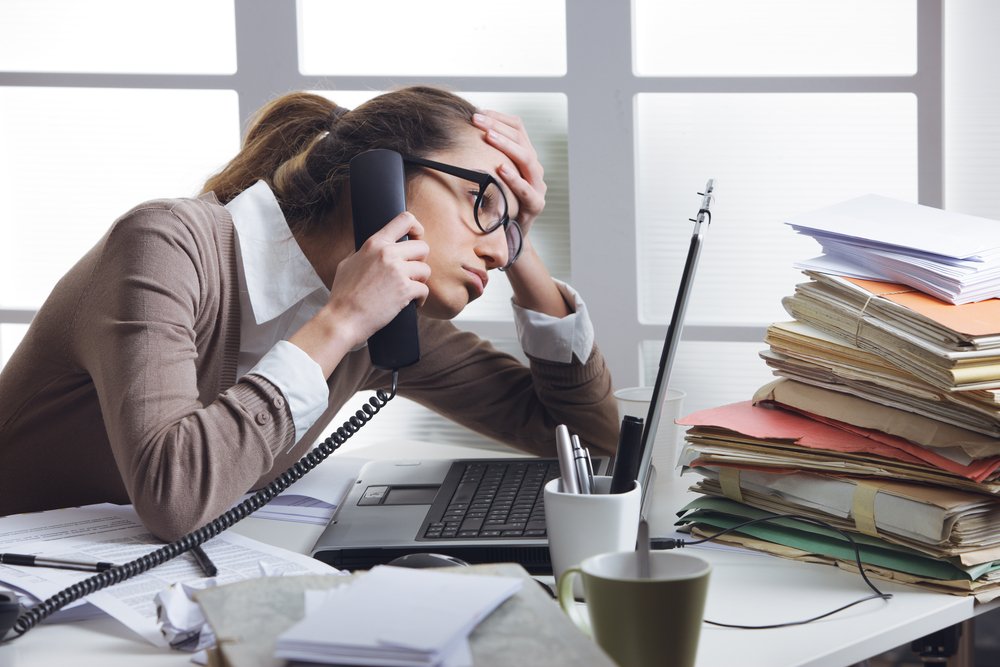 A stressed business woman looks tired she answer telephones in her office