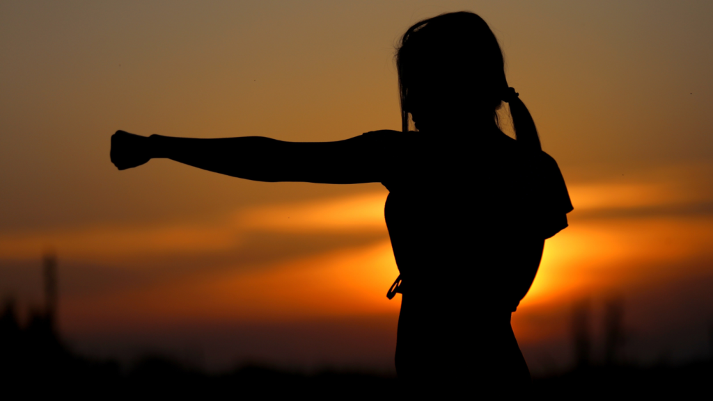 woman silhouette fighting in sunset
