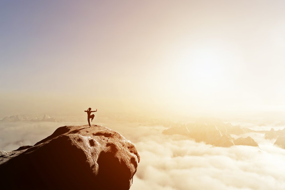 Asian man, fighter practices martial arts in high mountains above clouds at sunset. Kung fu and karate pose. Also concepts of discipline, concentration, meditaion etc. Unique