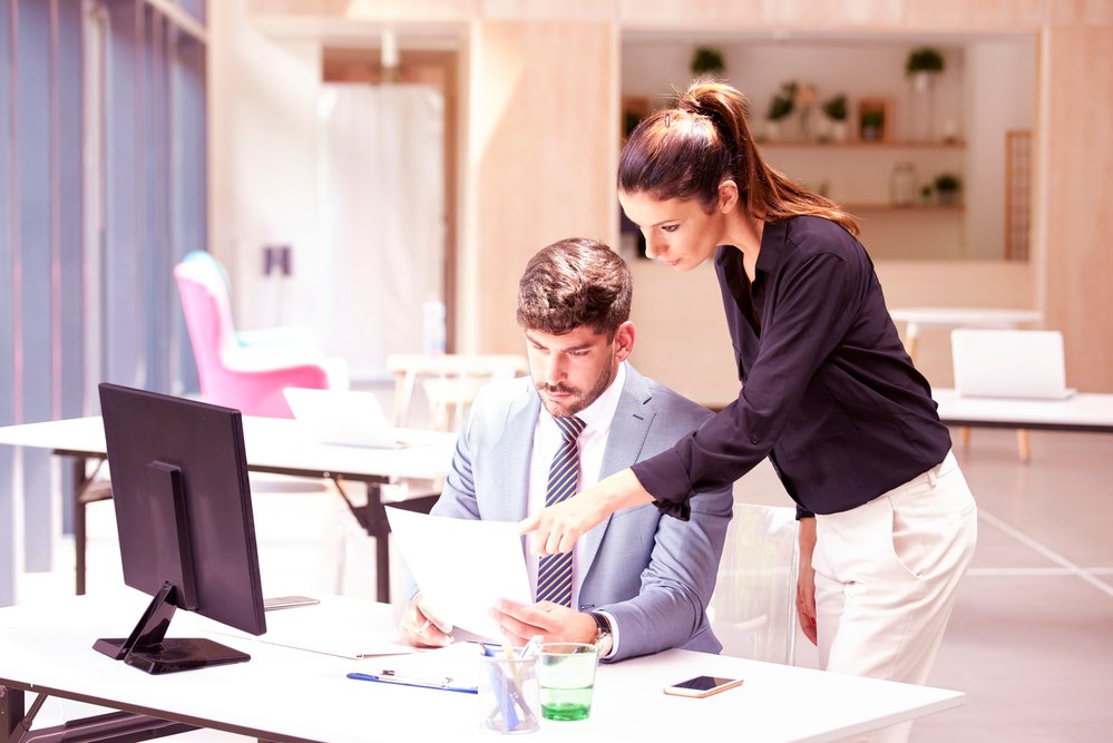 Group of business people working together on new project. Investment advisor businessman sitting in front of computer while consulting with an attractive business woman.