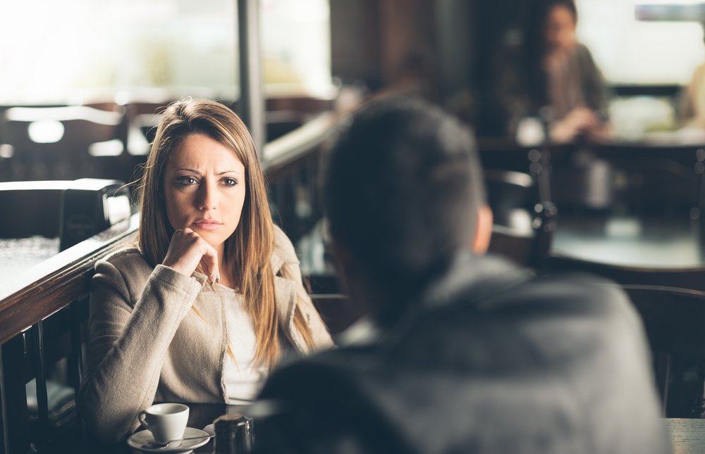 Friends at the bar, he is giving her bad news