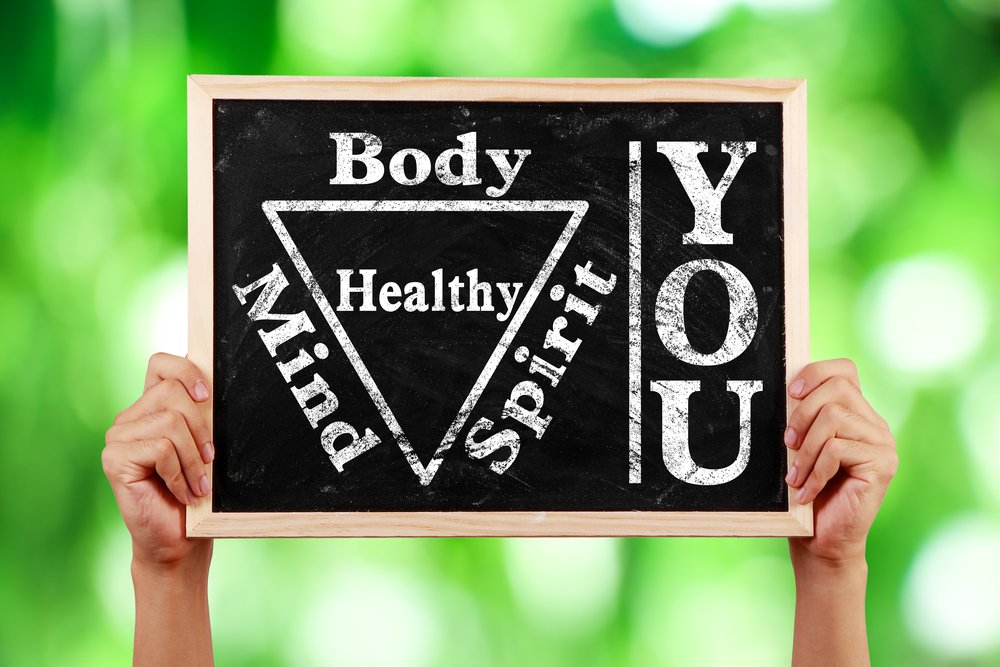 Hands holding blackboard with text You Body Spirit Soul Mind Healthy against green blurred background.